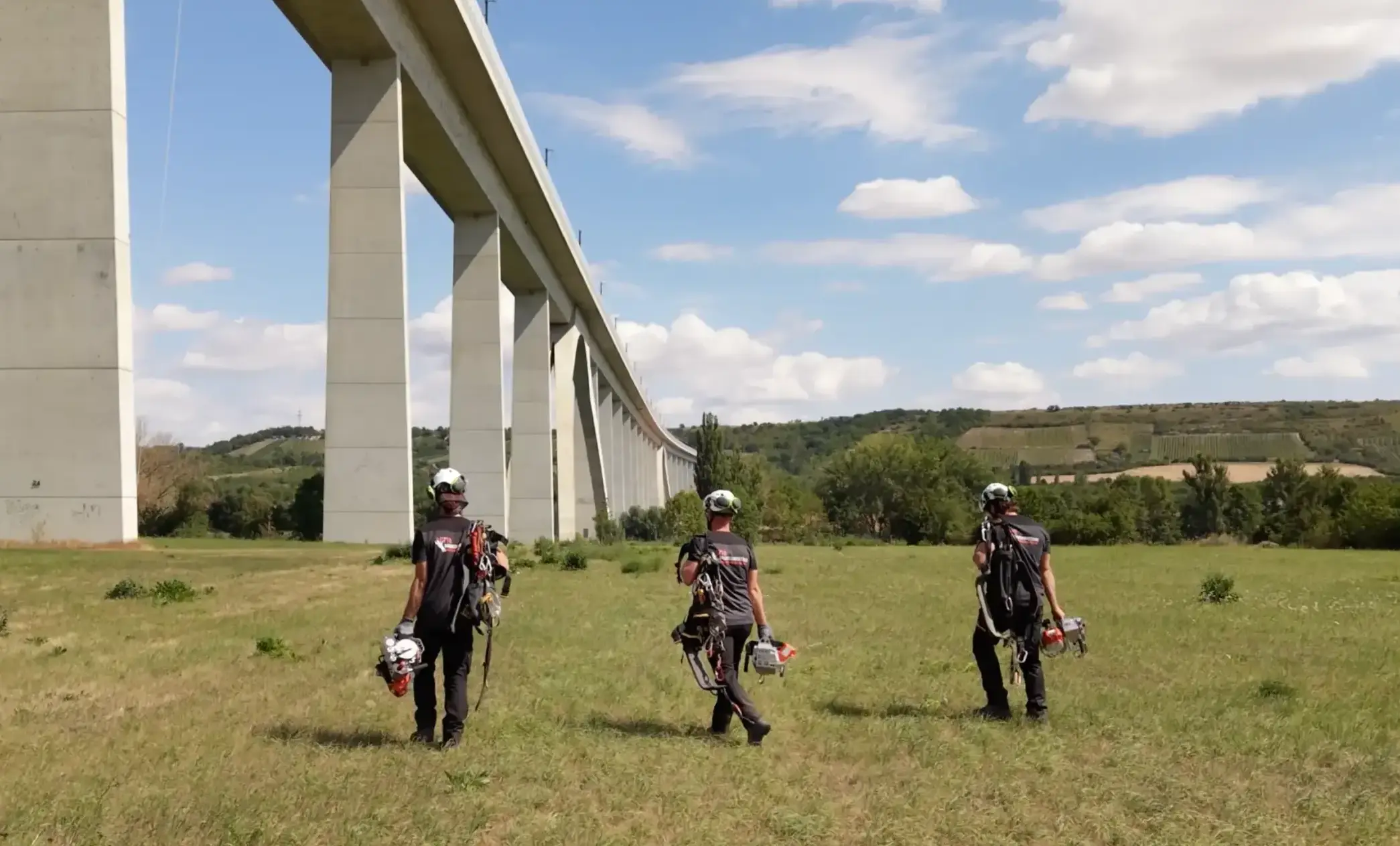 3 Industriekletterer auf dem Weg zur Baustelle an einer Brücke